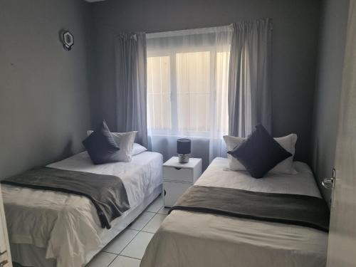 two beds in a room with a window at Ingwe Manor Guesthouse in Margate