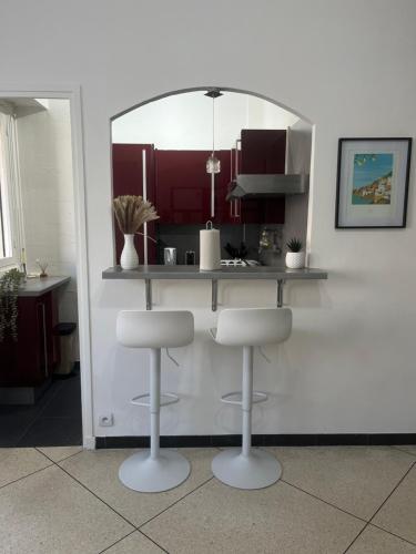 une cuisine avec un comptoir avec deux tabourets et un miroir dans l'établissement Nice Séjour Detente Studio Lumineux Balcon Cuisine Equipée Wifi, à Nice