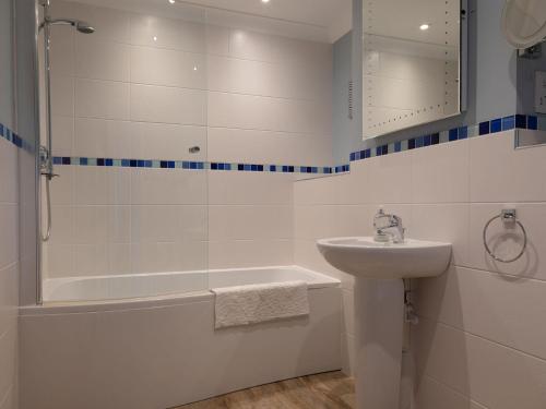 a white bathroom with a sink and a tub and a shower at 17 St Elmo Court in Salcombe
