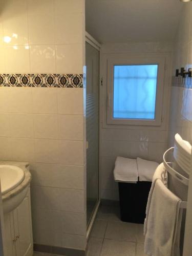 une salle de bain blanche avec un lavabo et une fenêtre dans l'établissement Maisonnette pour 4 pers piscine de mai à sept 2hrs par jour, à Dagneux