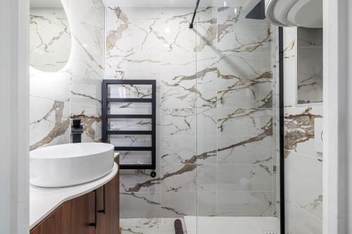 La salle de bains est pourvue d'un lavabo et d'un mur en marbre. dans l'établissement 10 ORANGERS - Magnifique studio climatise - Les Clementines, à Nice