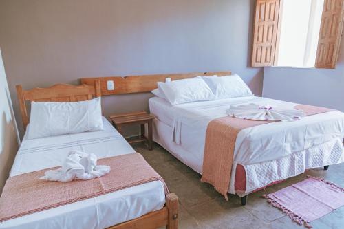 a bedroom with two beds with towels on them at Pousada Porto Da Barra in Porto Seguro