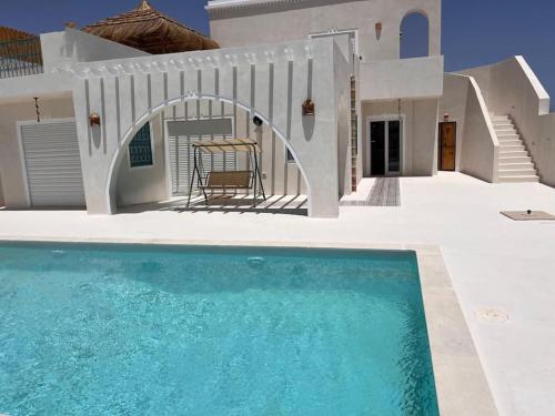 a villa with a swimming pool in front of a house at Dar el Ànbar in Midoun