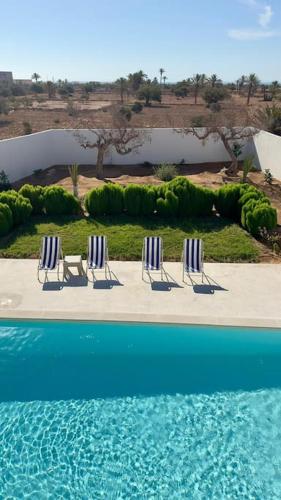 three blue and white chairs sitting next to a pool at Dar el Ànbar in Midoun