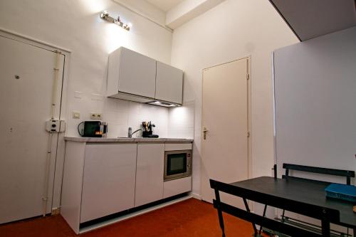 une cuisine avec des armoires blanches et une table à l'intérieur dans l'établissement New! Joli T2 mezzanine en centre ville, à Aix-en-Provence