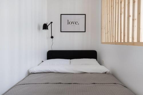a bed in a white room with a picture on the wall at Hook Studios Vilnius Old Town in Vilnius