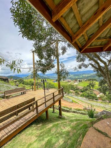 a wooden bench sitting under a roof with a view at Chalés Encanto Das Pedras - Chalé Super Luxo in Sapucaí-Mirim