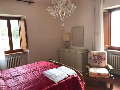 a bedroom with a bed and a chair and a chandelier at Casa delle Sirene in Perugia