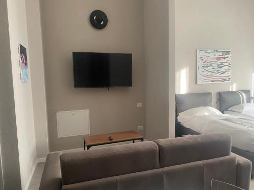 a living room with a couch and a tv on the wall at Residenza Segrate Centro Novegro in Segrate