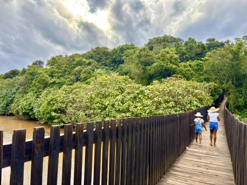 two people walking on a wooden bridge over a river at Mtunzini Forest Lodge Self Catering Resort in Mtunzini