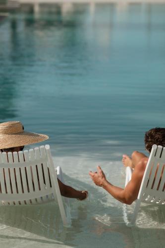 a man sitting in the water next to two chairs at Delano Dubai at Bluewaters in Dubai