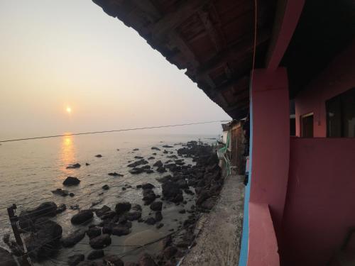a group of rocks in the water at sunset at Om Ganesh Guest House Cliffside in Arambol