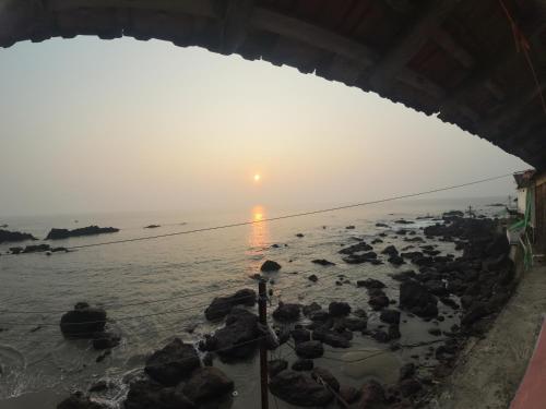 a view of the beach at sunset from a building at Om Ganesh Guest House Cliffside in Arambol