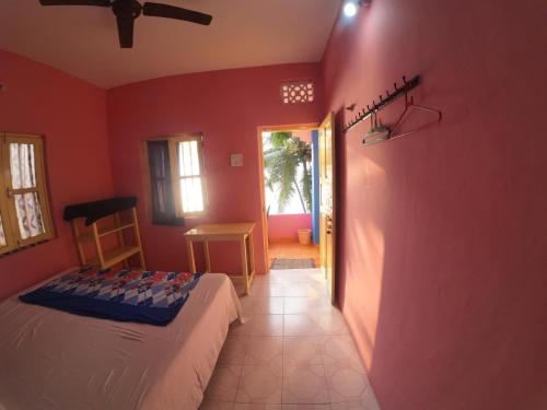 a bedroom with a bed in a room with red walls at Om Ganesh Guest House Cliffside in Arambol