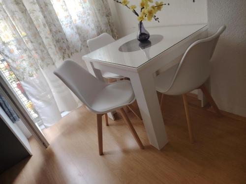 un tavolo bianco con sedie e un vaso con fiori di Cozy Max Studio a Jagodina