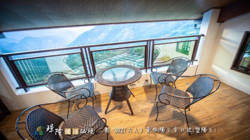 a balcony with tables and chairs and a large window at 璟隆慢活仙境民宿 in Kung-t'ien-ts'un