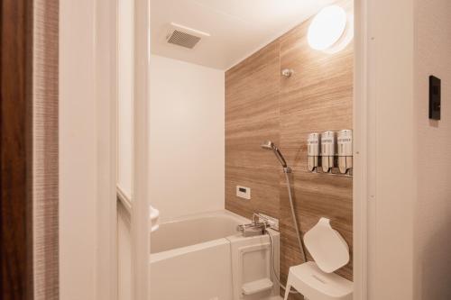 a bathroom with a white tub and a toilet at The LOFT INN HAKATA in Fukuoka