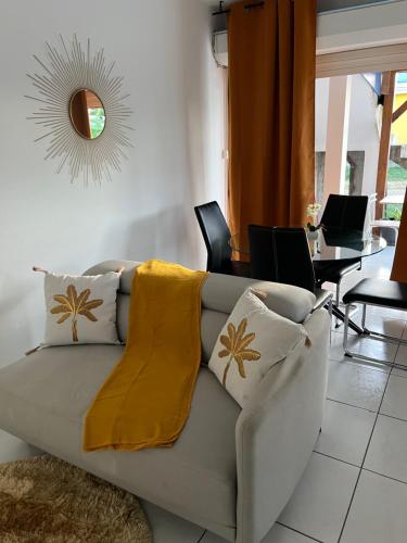 a living room with a couch with a yellow blanket on it at L’Eucalyptus in Sainte-Rose