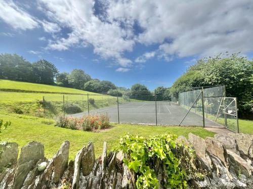 a tennis court with a net in a field at 3 bedroom barn conversion with swimming pool, tennis court and more! in Kingsbridge