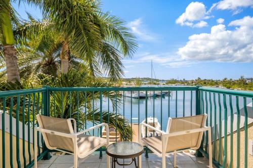 a balcony with chairs and a table and a view of the water at Exquisite Yacht Club Townhome in The Bight Settlements