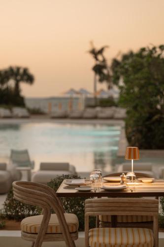 a wooden table and chairs with a table and a pool at Delano Dubai at Bluewaters in Dubai