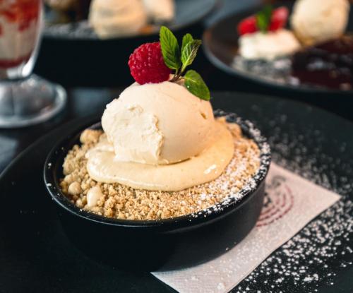 a dessert with ice cream and a raspberry on a black plate at Great National South Court Hotel in Limerick