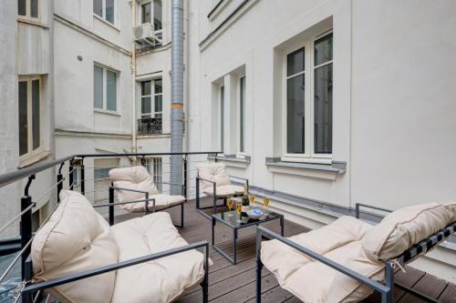 un balcon avec des chaises et une table sur un immeuble dans l'établissement Bluestay 290 - Superbe appartement à Paris 17, à Paris