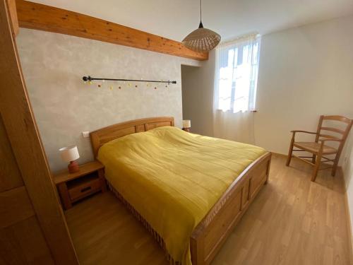 une chambre avec un grand lit avec un couvre-lit jaune dans l'établissement Maison de famille Les Hirondelles, à Saint-Maurice-sur-Fessard