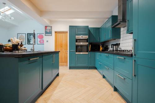 a blue kitchen with black counter tops and blue cabinets at Acer View in Leeds
