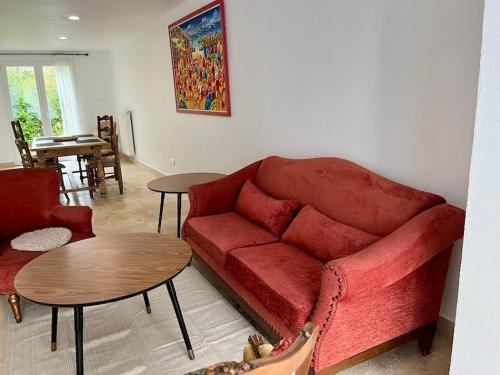a living room with a red couch and tables at Symphonie Gîte Appartement meublé in Gréoux-les-Bains