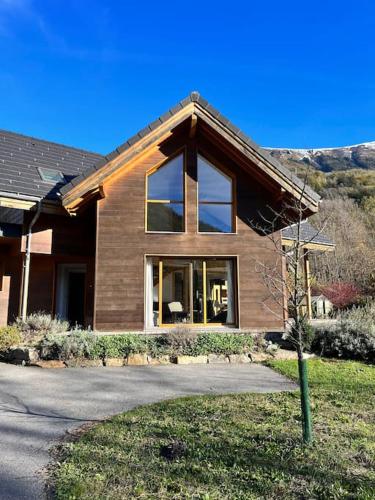 une maison avec une grande fenêtre sur une rue dans l'établissement Maison Blanche, Impressive Chalet, Allemond, Bike, Ski, Hike, à Allemont
