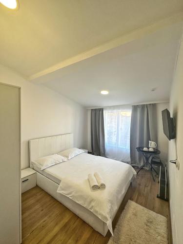 Un dormitorio con una cama blanca y una ventana. en Residence Ultracentral Brasov, en Brasov