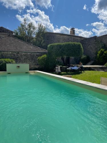 une piscine avec de l'eau bleue dans une cour dans l'établissement Maison de charme en Provence, à Aubussargues