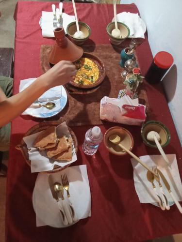 a table with a red table cloth with food on it at Adil Guest House in Nzala