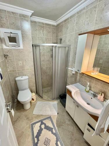a bathroom with a shower and a toilet and a sink at Manolyam suit havuzlu 2+1 in Kaş