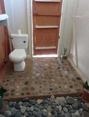 a bathroom with a toilet and a door with rocks on the floor at Vanista Dica- Dancing Bamboo in Isle