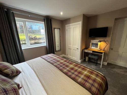 a bedroom with a bed and a desk and a television at The Garden Rooms in Newport-On-Tay