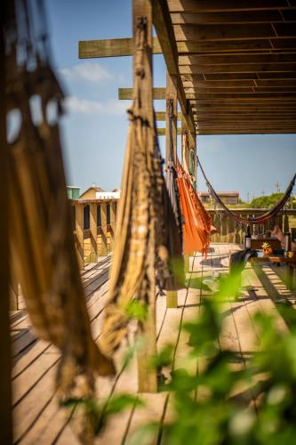 a hammock on a wooden deck with a bridge at Compay Hostel Punta del Diablo in Punta Del Diablo