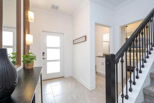 a hallway with a staircase and aoyer with white walls at 2557 Awesome Family 4BD Townhouse located at Storey Lake in Kissimmee
