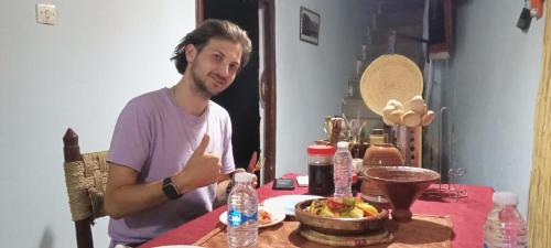 a man sitting at a table with a bowl of food at Adil Guest House in Nzala