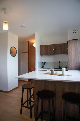 une cuisine avec un comptoir blanc et des tabourets dans l'établissement Appartement La Biche, à Combloux