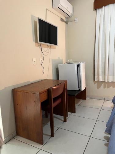 a room with a desk and a tv on the wall at Hotel Muller in Mariana