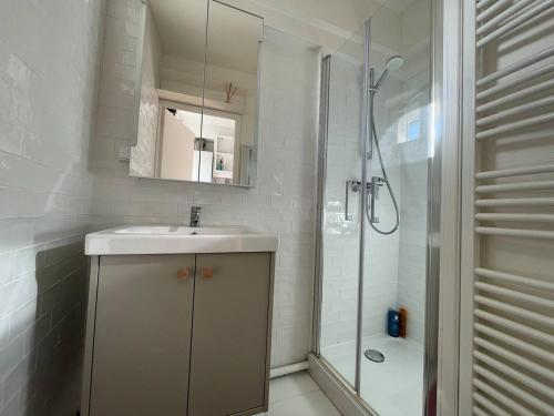 ein weißes Badezimmer mit Waschbecken und Dusche in der Unterkunft La PetiteVillaise in Granville