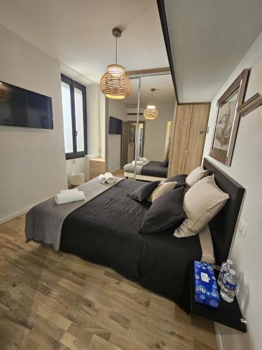 - une chambre avec un grand lit noir et des oreillers dans l'établissement PALOMA, à Cannes