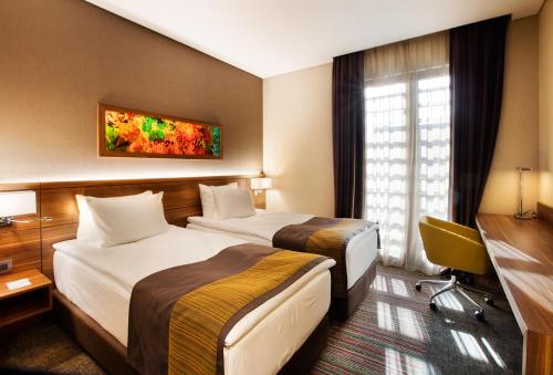 イスタンブールにあるHoliday Inn Istanbul - Kadikoy, an IHG Hotelのベッド2台とデスクが備わるホテルルームです。