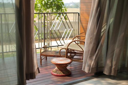 a porch with a bench and a table and a stool at Navela Hotel & Convention in Ratchaburi