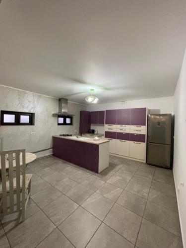 a large kitchen with purple cabinets and a refrigerator at Holidays Home 4 You in Rădăuţi