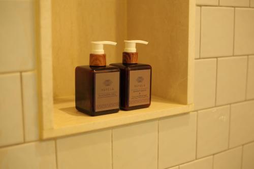 two bottles ofodorizers sitting on a shelf in a bathroom at Navela Hotel & Convention in Ratchaburi