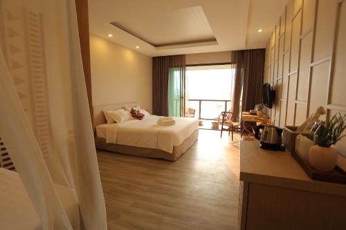 a hotel room with a bed and a large window at Navela Hotel & Convention in Ratchaburi