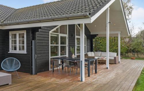 a patio with a black house with a table and chairs at Lovely Home In Dannemare With Sauna in Dannemare